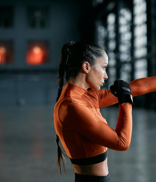Woman performing a light cardio exercise in a modern, dark studio.